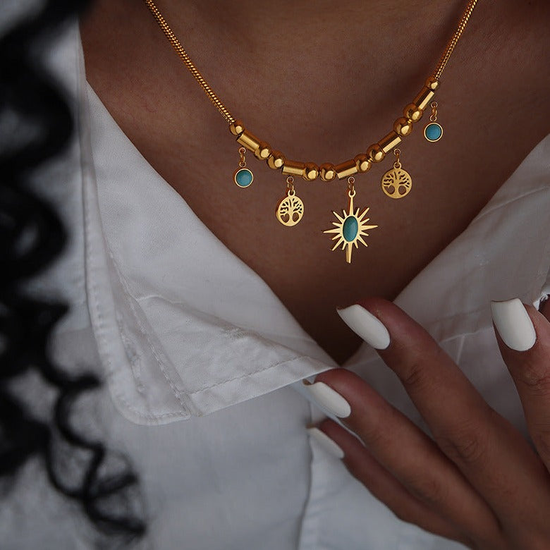 Gold and Blue stone necklace featuring a star and trees on a models neck